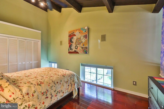 bedroom featuring beam ceiling, dark wood finished floors, baseboards, and a closet