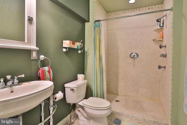 bathroom featuring toilet, a sink, a shower stall, and tile patterned flooring