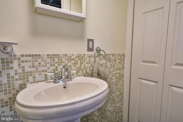 bathroom with tile walls, a sink, and a wainscoted wall