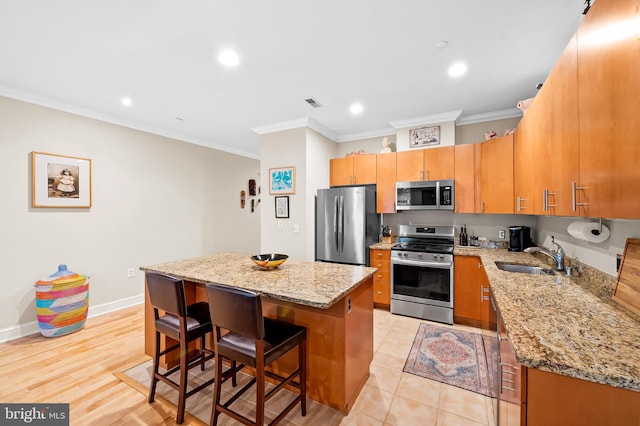 2007 Clipper Park Rd Unit 114, Baltimore, MD 21211 - kitchen with appliances with stainless steel finishes, a sink, ornamental molding, a breakfast bar area, and a center island