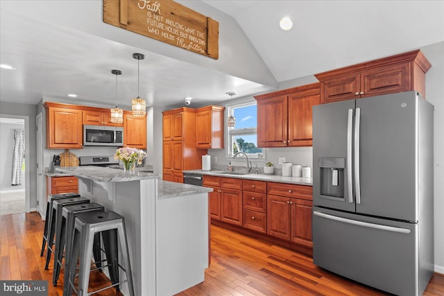 34602 Roxana Rd, Frankford, DE 19945 - kitchen featuring appliances with stainless steel finishes, vaulted ceiling, a sink, light wood-style floors, and a kitchen breakfast bar
