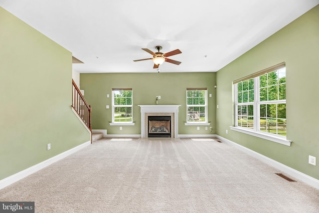 26635 Del Ibera Ct, Mechanicsville, MD 20659 - unfurnished living room featuring a fireplace with flush hearth, ceiling fan, baseboards, stairway, and carpet floors
