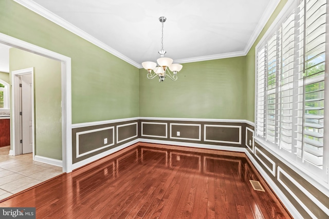 26635 Del Ibera Ct, Mechanicsville, MD 20659 - unfurnished dining area featuring a chandelier, ornamental molding, wood finished floors, and wainscoting