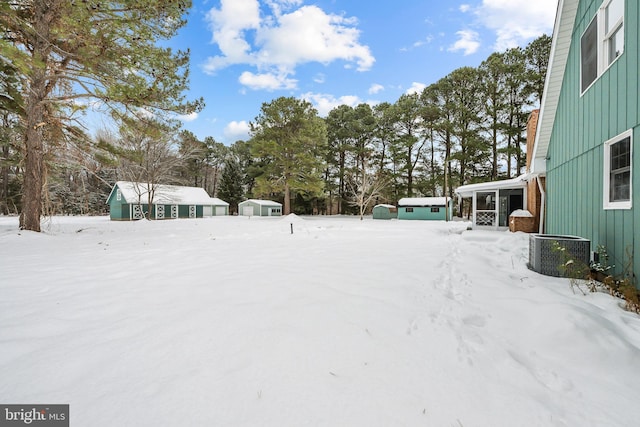21830 Vaughn Rd, Georgetown, DE 19947 - snowy yard featuring cooling unit, view of wooded area, and a storage shed