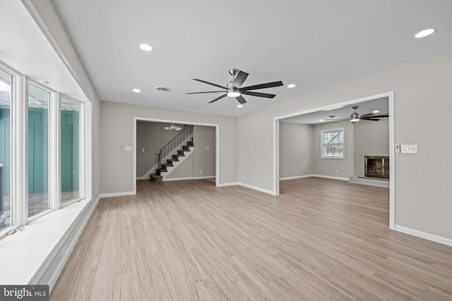 21830 Vaughn Rd, Georgetown, DE 19947 - unfurnished living room with stairs, baseboards, light wood-style floors, a ceiling fan, and a fireplace