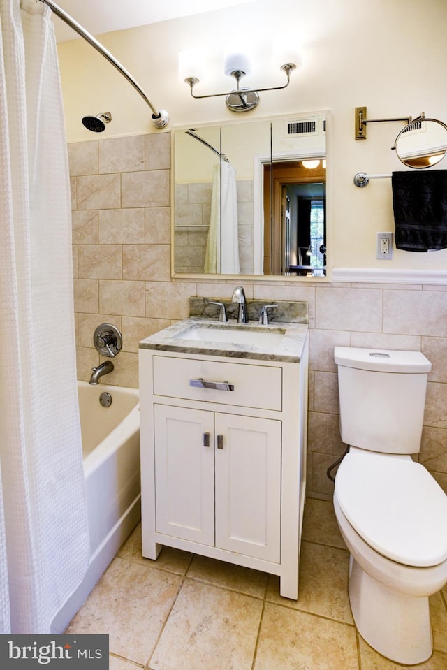 bathroom with tile walls, tile patterned flooring, toilet, vanity, and shower / bath combo with shower curtain