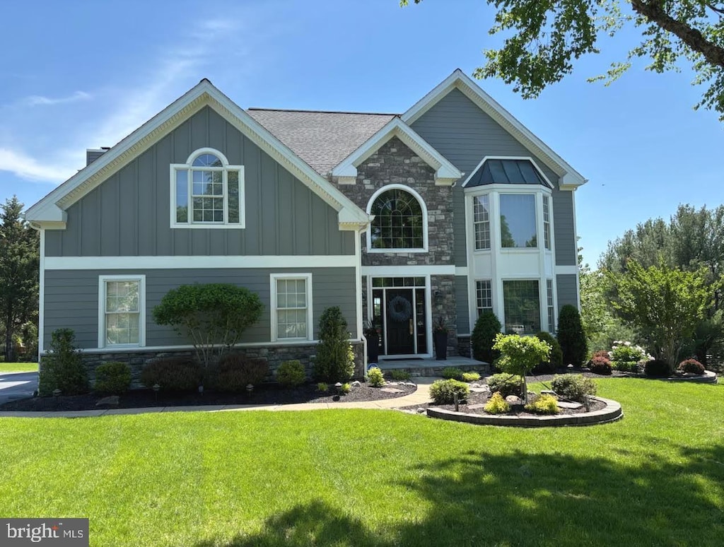 view of front of home with stone siding, board and batten siding, and a front yard