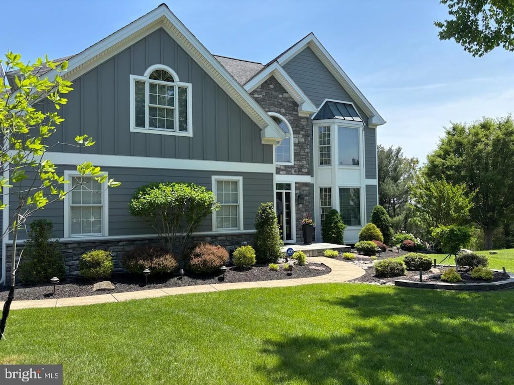 view of front facade with stone siding, board and batten siding, and a front yard