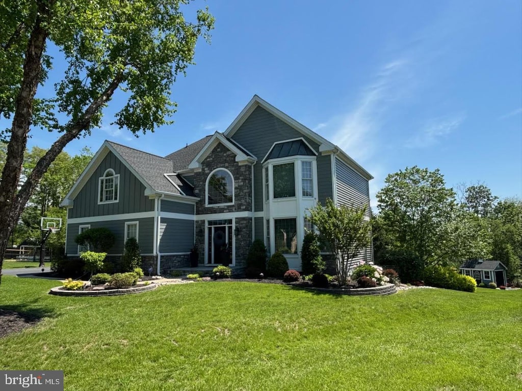 view of front of home featuring stone siding, a front lawn, and board and batten siding