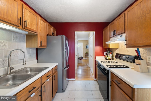 104 Braeburn Dr, Winchester, VA 22601 - kitchen featuring under cabinet range hood, gas stove, a sink, brown cabinetry, and light countertops
