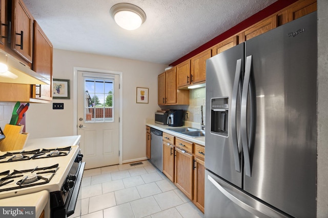 104 Braeburn Dr, Winchester, VA 22601 - kitchen featuring appliances with stainless steel finishes, light countertops, a sink, brown cabinets, and light tile patterned flooring