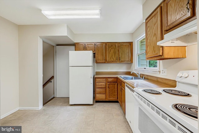 kitchen featuring white appliances, a sink, under cabinet range hood, brown cabinets, and light countertops