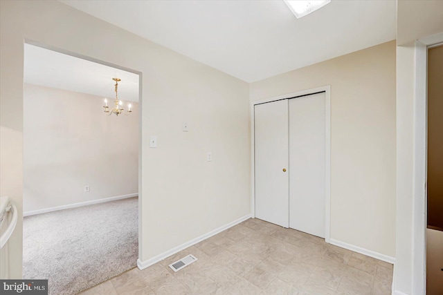 unfurnished bedroom featuring a chandelier, baseboards, a closet, and light carpet