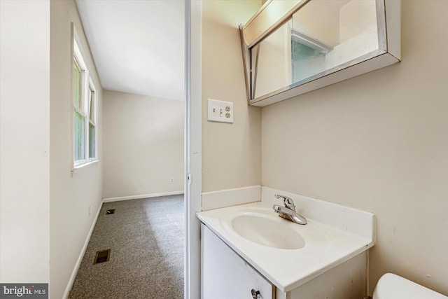 half bathroom with vanity, toilet, and baseboards