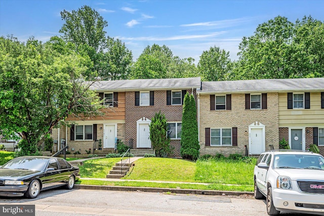 view of property with brick siding and a front yard