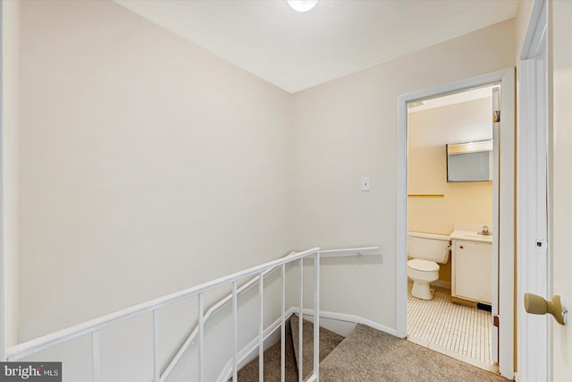corridor with carpet flooring, baseboards, and a sink