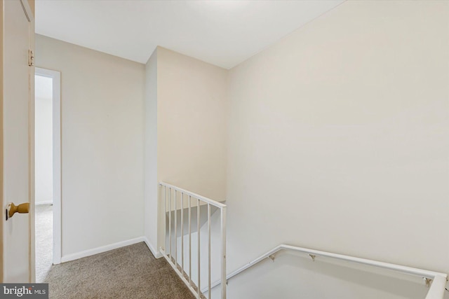 corridor featuring carpet flooring, an upstairs landing, and baseboards