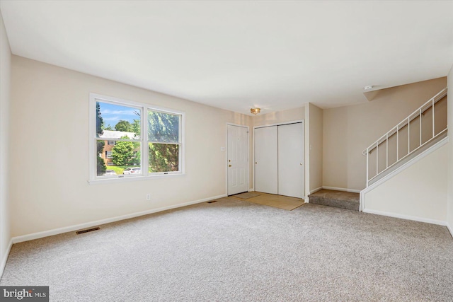 unfurnished living room with carpet flooring, stairway, and baseboards