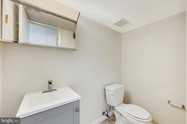 half bathroom featuring baseboards, toilet, vanity, and tile patterned floors