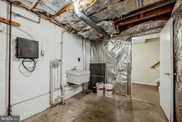 unfinished basement with a sink, concrete block wall, and stairs