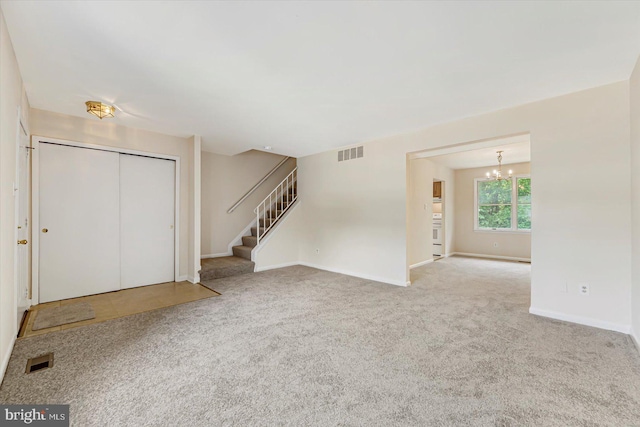 carpeted entryway featuring a chandelier, stairway, and baseboards