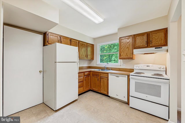 kitchen with white appliances, under cabinet range hood, a sink, brown cabinets, and light countertops