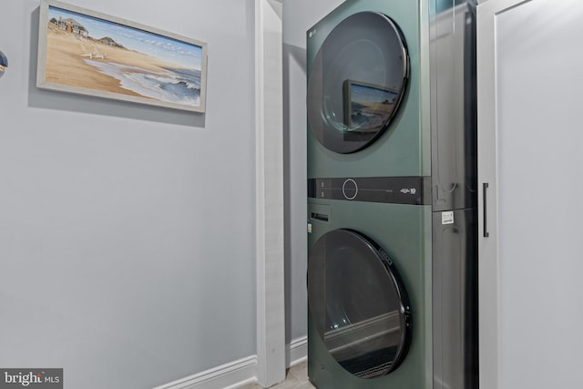 laundry area featuring stacked washer / drying machine and baseboards