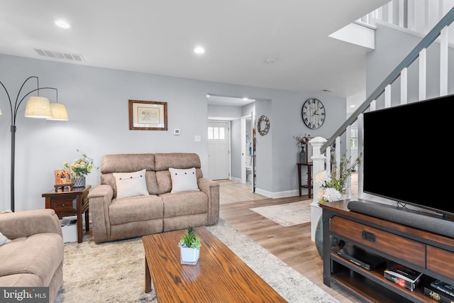 living area featuring stairway, baseboards, light wood finished floors, and recessed lighting