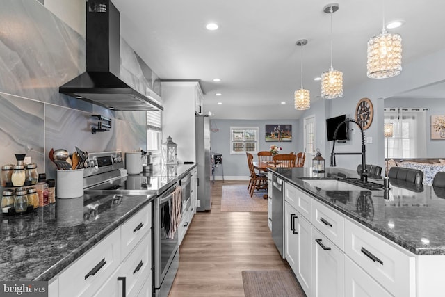kitchen featuring appliances with stainless steel finishes, wall chimney range hood, a sink, a chandelier, and recessed lighting
