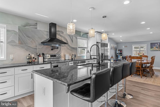 kitchen featuring appliances with stainless steel finishes, wall chimney range hood, a sink, recessed lighting, and light wood-type flooring