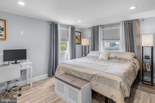 bedroom with multiple windows, an office area, light wood-type flooring, baseboards, and recessed lighting