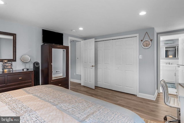 bedroom featuring baseboards, wood finished floors, recessed lighting, and a closet