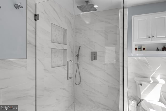 bathroom featuring a marble finish shower and toilet