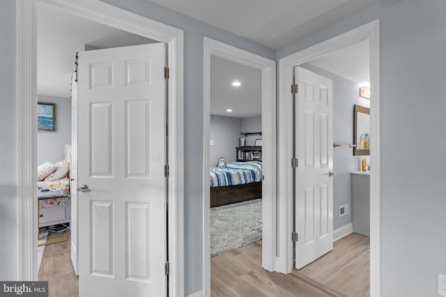 hall with light wood-style flooring and baseboards