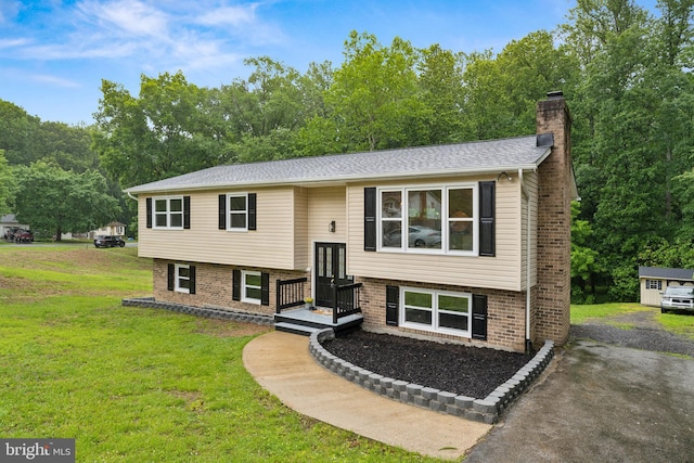 39743 Daniel Cir, Mechanicsville, MD 20659 - split foyer home featuring a chimney, brick siding, a front lawn, and view of scattered trees