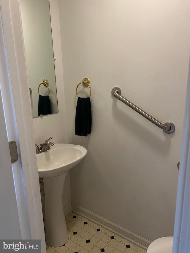 half bath featuring tile patterned floors and baseboards