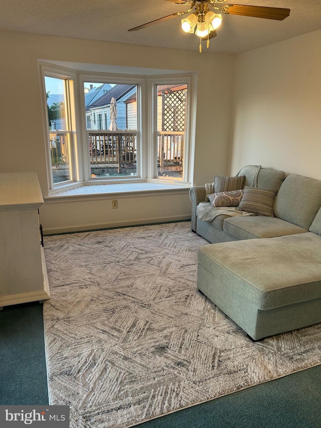 carpeted living room with a ceiling fan and baseboards