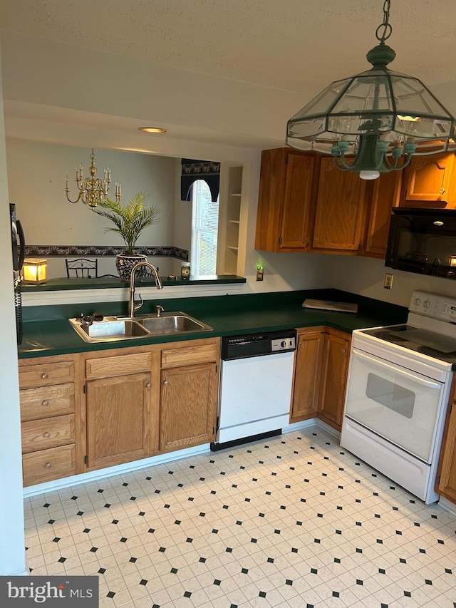 kitchen featuring white appliances, a sink, a chandelier, dark countertops, and brown cabinetry