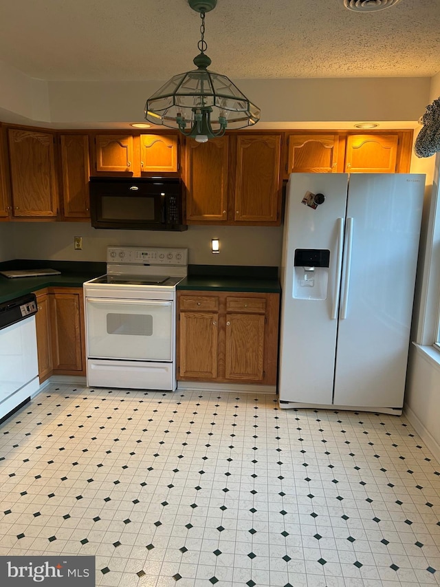 kitchen featuring white appliances, dark countertops, brown cabinetry, and decorative light fixtures
