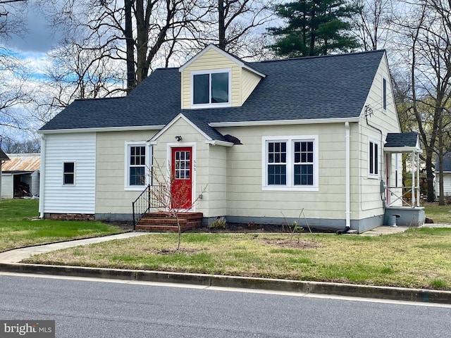 new england style home with roof with shingles and a front lawn