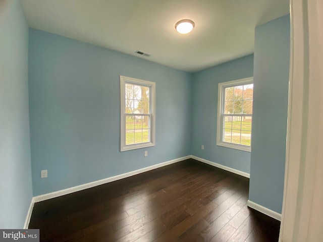 unfurnished room with dark wood finished floors and baseboards