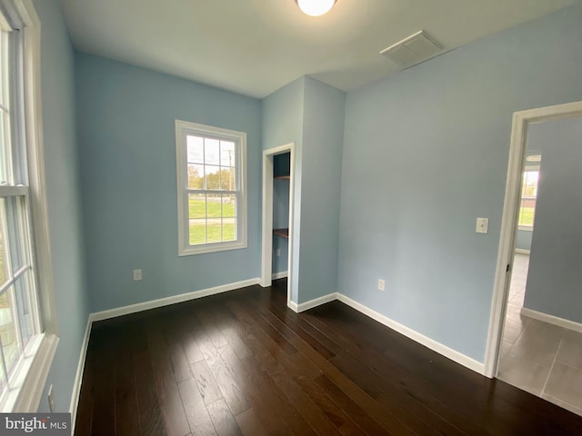 unfurnished bedroom with dark wood-type flooring and baseboards