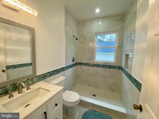 full bath featuring tile walls, tiled shower, toilet, and vanity