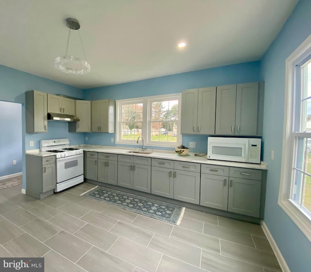 kitchen featuring white appliances, under cabinet range hood, a sink, and light countertops
