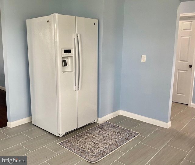 kitchen featuring white refrigerator with ice dispenser, baseboards, and wood finish floors