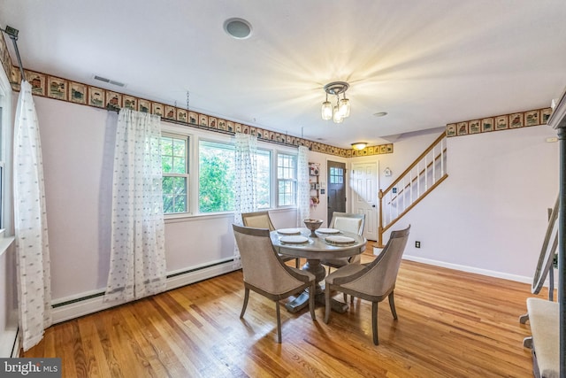 dining room with a baseboard radiator, wood finished floors, stairs, and baseboards