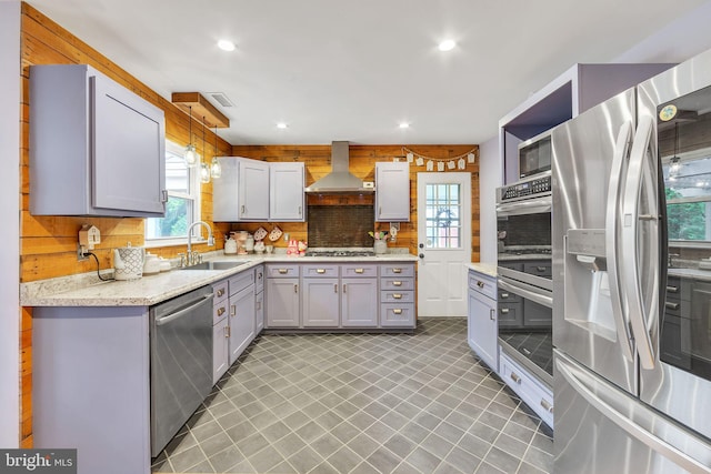 kitchen featuring stainless steel appliances, a sink, wall chimney exhaust hood, backsplash, and recessed lighting