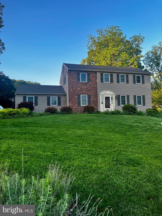 colonial inspired home featuring a front lawn and brick siding