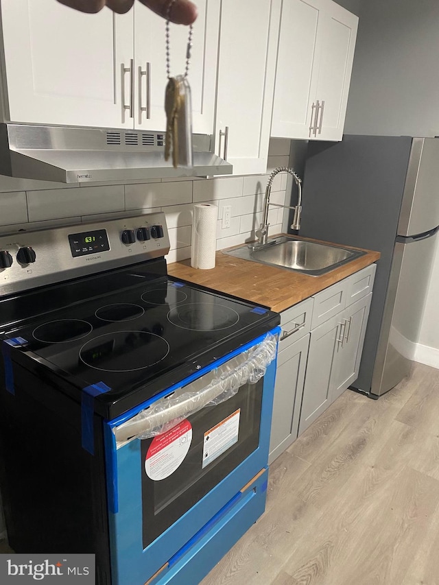 4951 W Thompson St, Philadelphia, PA 19131 - kitchen featuring stainless steel appliances, a sink, light wood-style flooring, wooden counters, and white cabinetry