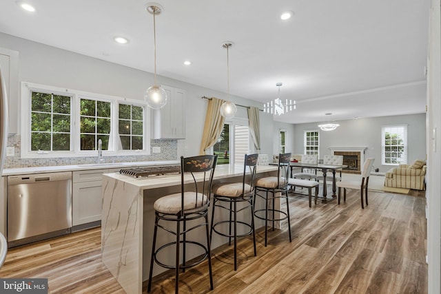 9310 Saffron Hill Ct, Manassas, VA 20110 - kitchen featuring stainless steel appliances, a sink, a center island, decorative backsplash, and light wood-style floors